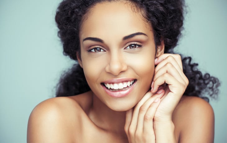 a woman smiling with her hands on her face