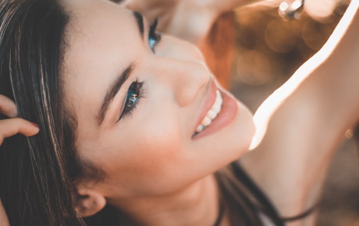 a woman smiling with her hand behind her head