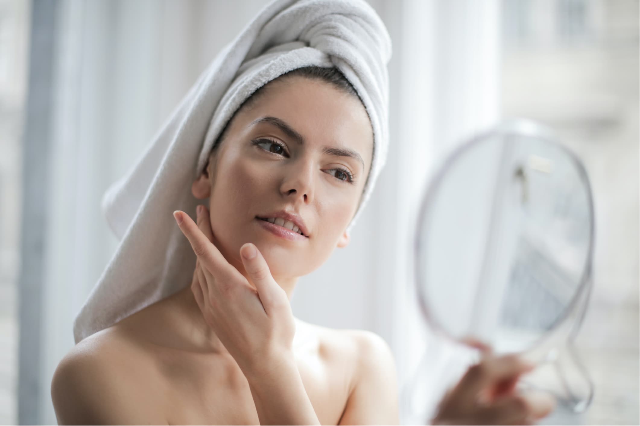 a woman with a towel on her head looking at her face