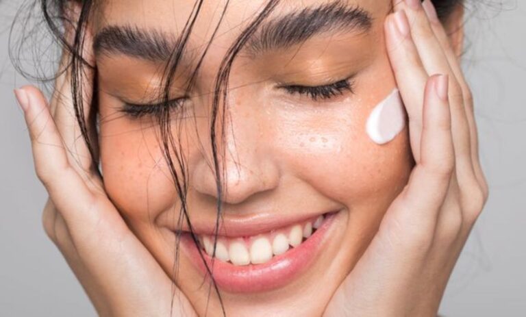 a woman smiling with her eyes closed and a lotion on her face