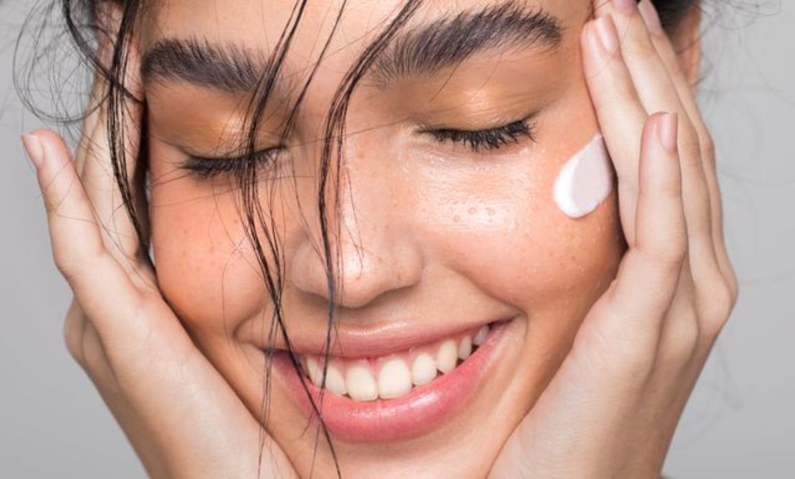 a woman smiling with her eyes closed and a lotion on her face