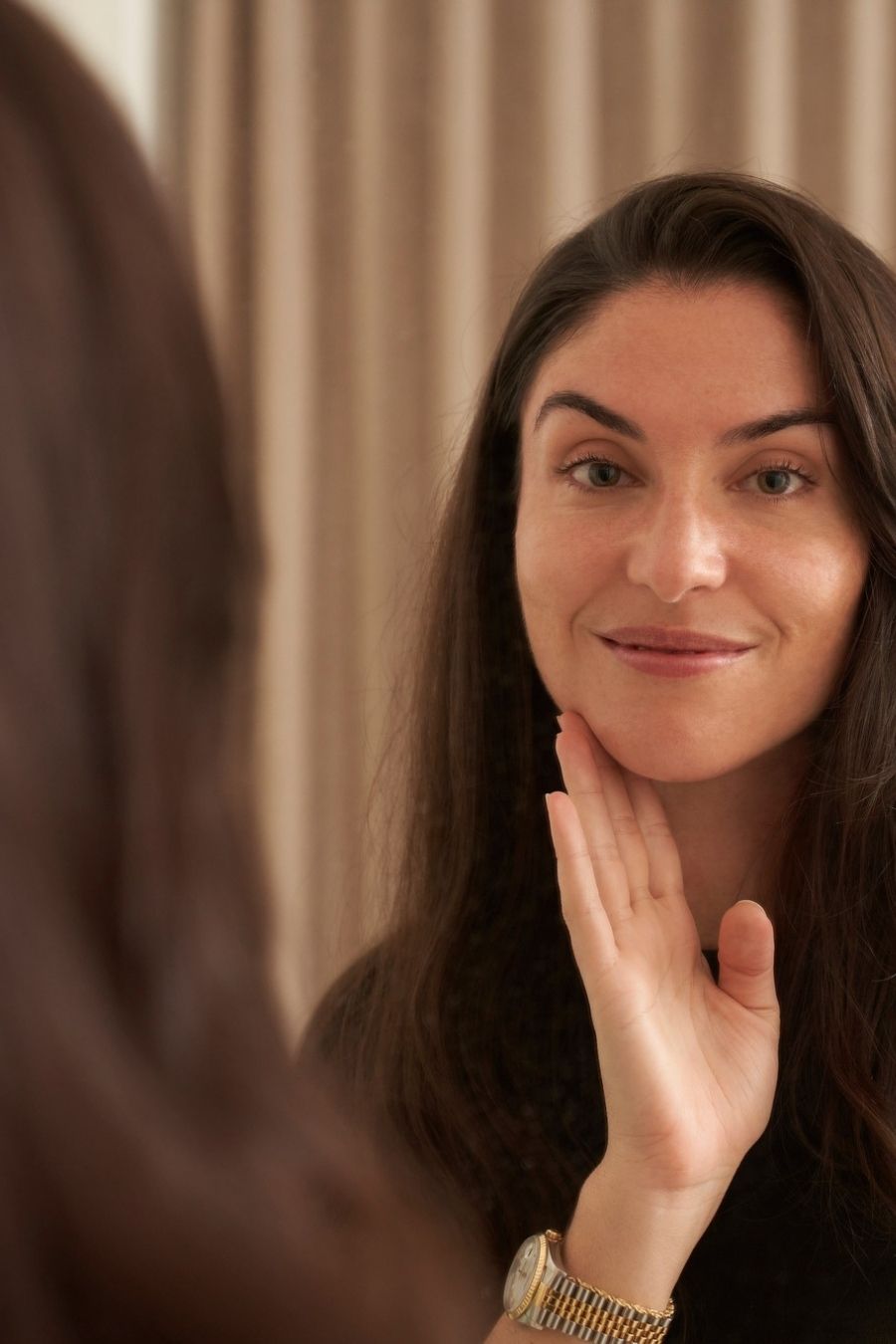 Closeup of woman looking at her beautiful skin in the mirror